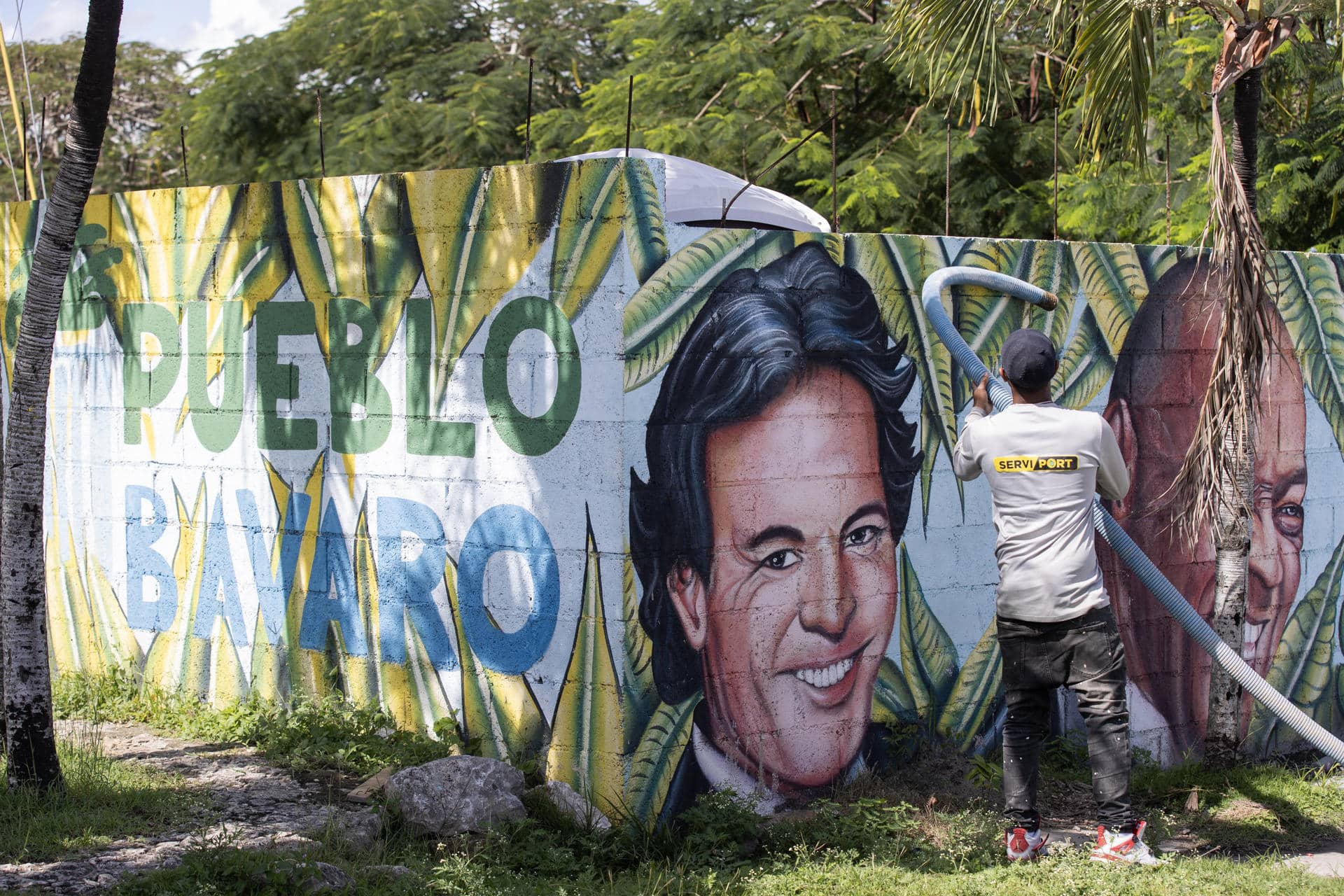 Una persona realiza labores de limpieza frente a un mural con los rostros de los artistas Julio Iglesias y Johnny Ventura en Punta Cana (República Dominicana). EFE/ Orlando Barría