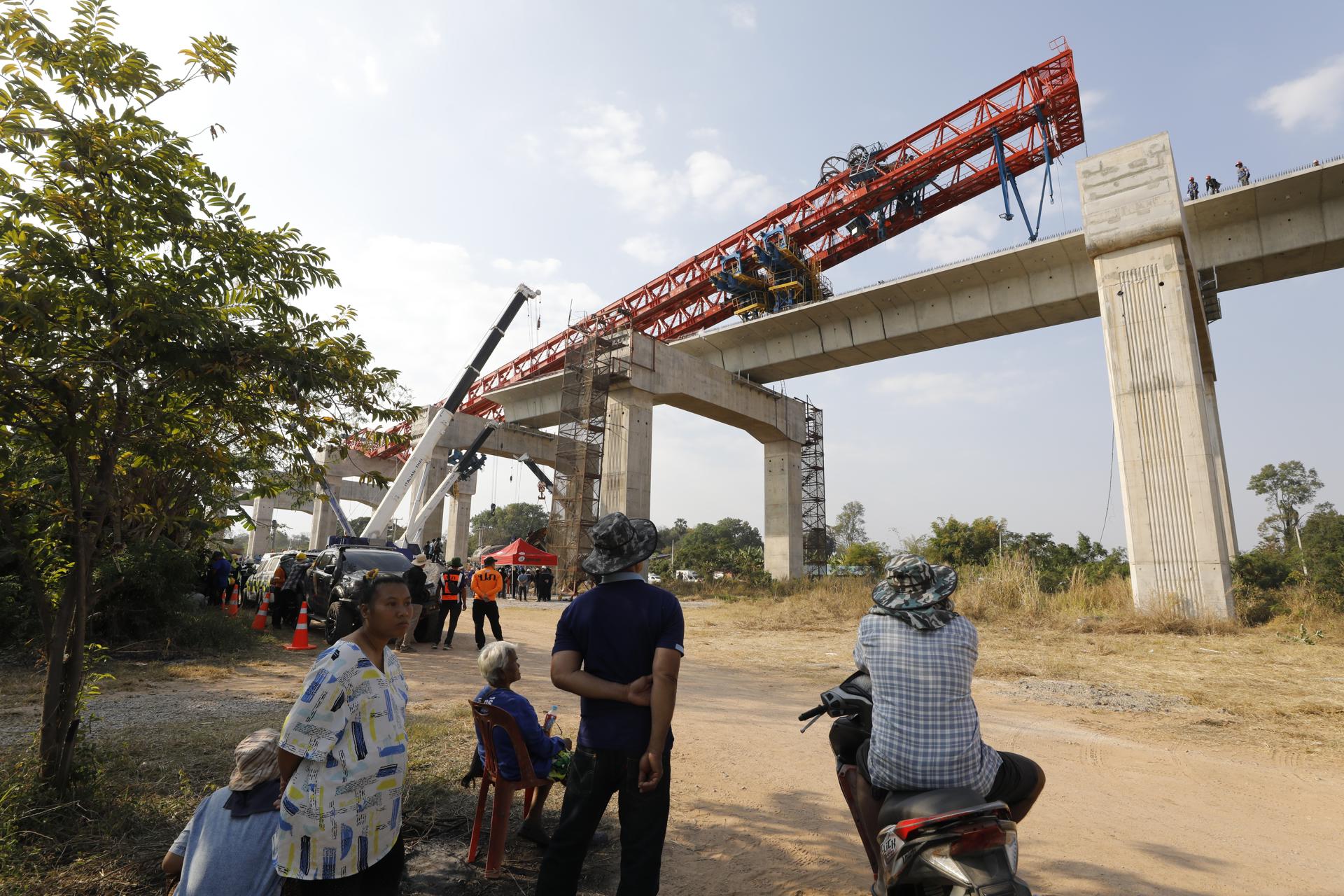 Sikhio (Thailand), 14/01/2026.- Rescuers work on the wreckage of a passenger train after a construction crane collapsed onto it in Sikhio district, Nakhon Ratchasima, Thailand, 14 January 2026. At least 32 people were killed and 64 others injured when a launching crane lifting a concrete slab fell onto the Special Express No. 21 train traveling from Bangkok to Ubon Ratchathani, according to the Ministry of Public Health. Thai Deputy Prime Minister and Minister of Transport Phiphat Ratchakitprakarn confirmed there were 195 passengers and staff on board the train at the time of the accident. (Tailandia) EFE/EPA/NARONG SANGNAK