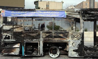 Iraníes caminan junto a los restos de un autobús público incendiado en Teherán, Irán, el 15 de enero de 2026. EFE/ Abedin Taherkenareh