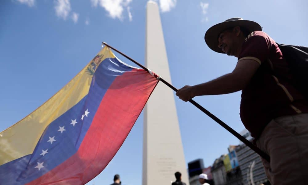 Un ciudadano venezolano ondea una bandera de su país durante una manifestación en apoyo a la intervención de Estados Unidos en Venezuela este domingo, frente al obelisco en Buenos Aires (Argentina). EFE/ Juan Ignacio Roncoroni
