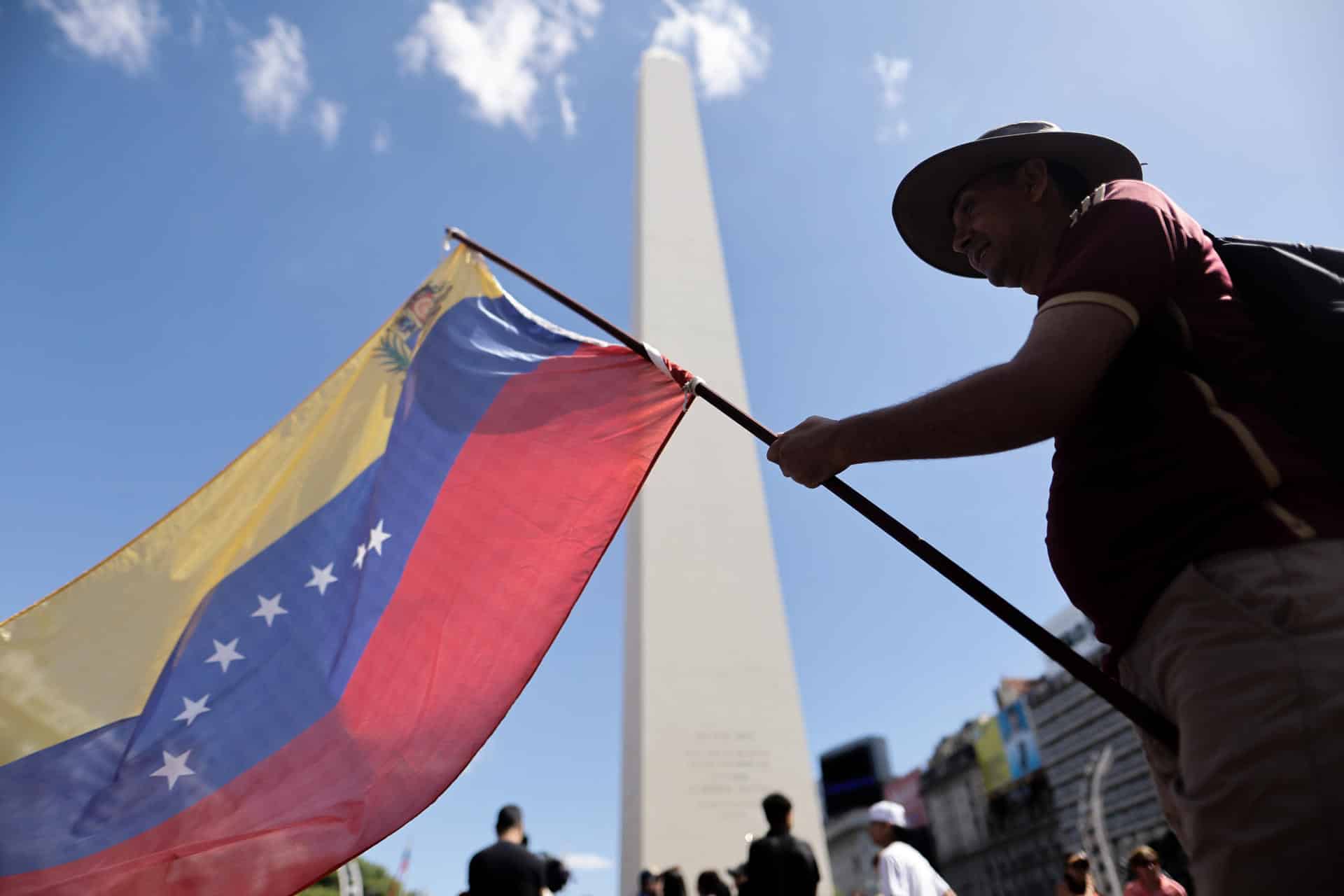 Un ciudadano venezolano ondea una bandera de su país durante una manifestación en apoyo a la intervención de Estados Unidos en Venezuela este domingo, frente al obelisco en Buenos Aires (Argentina). EFE/ Juan Ignacio Roncoroni