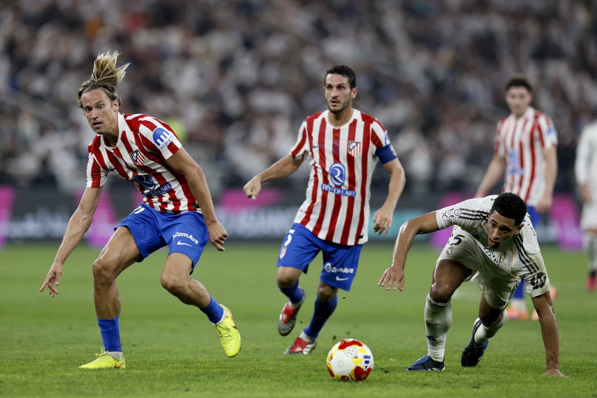 El centrocampista del Real Madrid Jude Bellingham (d) disputa un balón con el centrocampista del Atlético de Madrid Marcos Llorente (i) durante la semifinal de la Supercopa de España entre el Atlético de Madrid y el Real Madrid, este jueves en el Estadio Rey Abdullah, en Yeda. EFE/Kai Forsterling