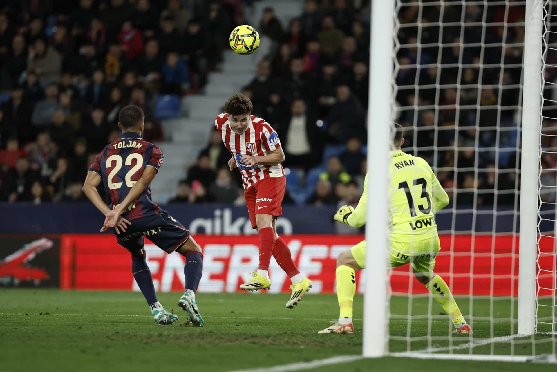 El delantero del Atlético de Madrid Julián Álvarez (c) remata a portería ante el defensa del Levante Jeremy Toljan (i) durante el encuentro correspondiente a la jornada 22 de LaLiga EA Sports entre Levante UD y Atlético de Madrid celebrado este sábado en el Estadio Ciutat de València. EFE/ Biel Aliño