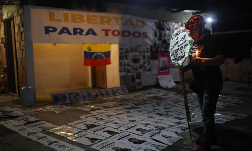 Fotografía del 15 de enero de 2026 de una mujer que observa imágenes de presos políticos durante una vigilia en los alrededores de la cárcel militar Ramo Verde este jueves, en Los Teques, estado de Miranda (Venezuela). EFE/ Miguel Gutiérrez
