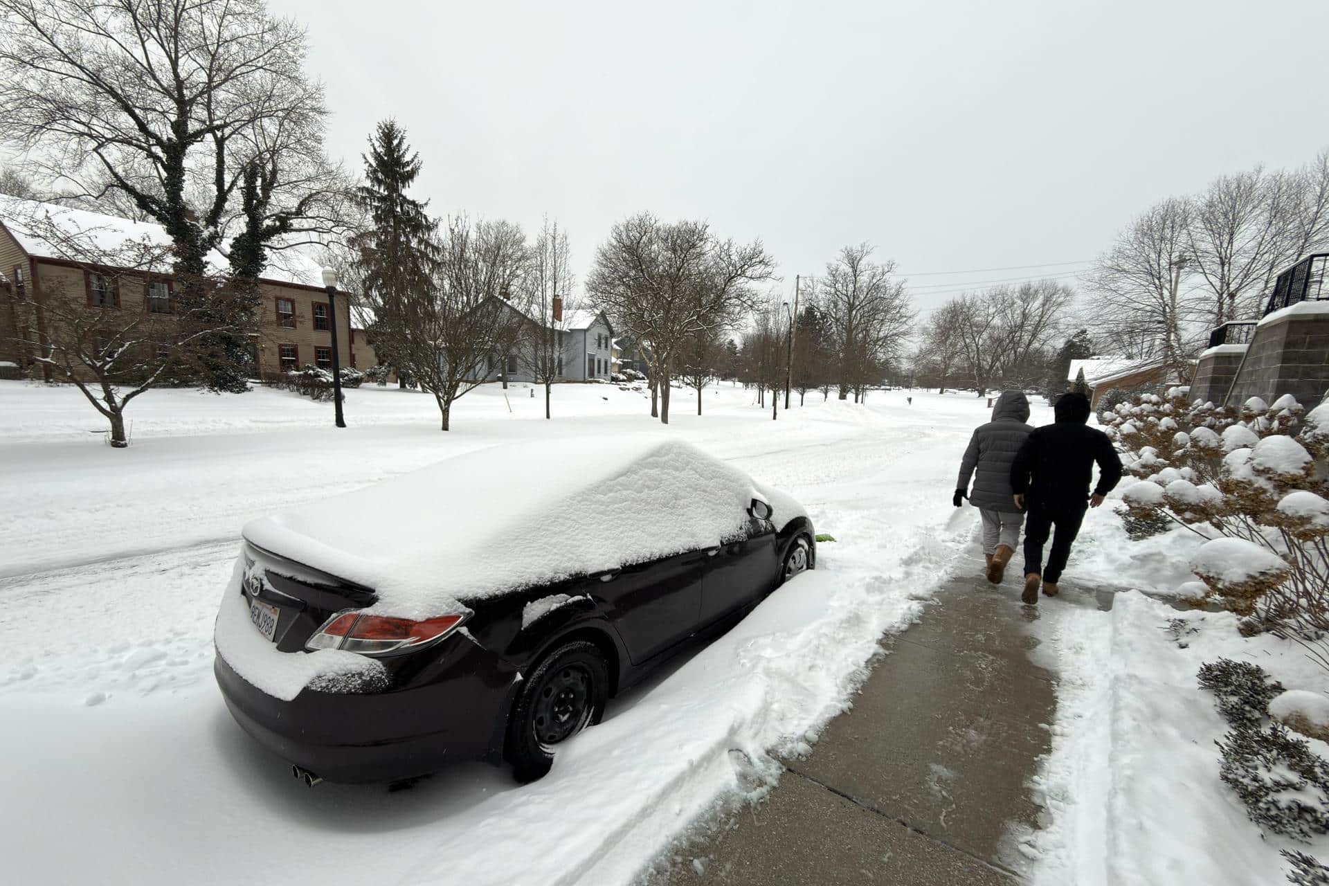 Dos personas caminan al lado de una calle afectada por la nieve este domingo en la ciudad de Hudson, Ohio (EE.UU.). EFE/ Rodrigo Sepúlveda