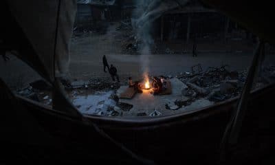 Palestinos desplazados se calientan cerca de un fuego entre las ruinas de su hogar destruido en Khan Yunis, en la franja de Gaza sur, el 30 de diciembre de 2025, en medio de un alto el fuego entre Israel y Hamas. 
EFE/EPA/HAITHAM IMAD