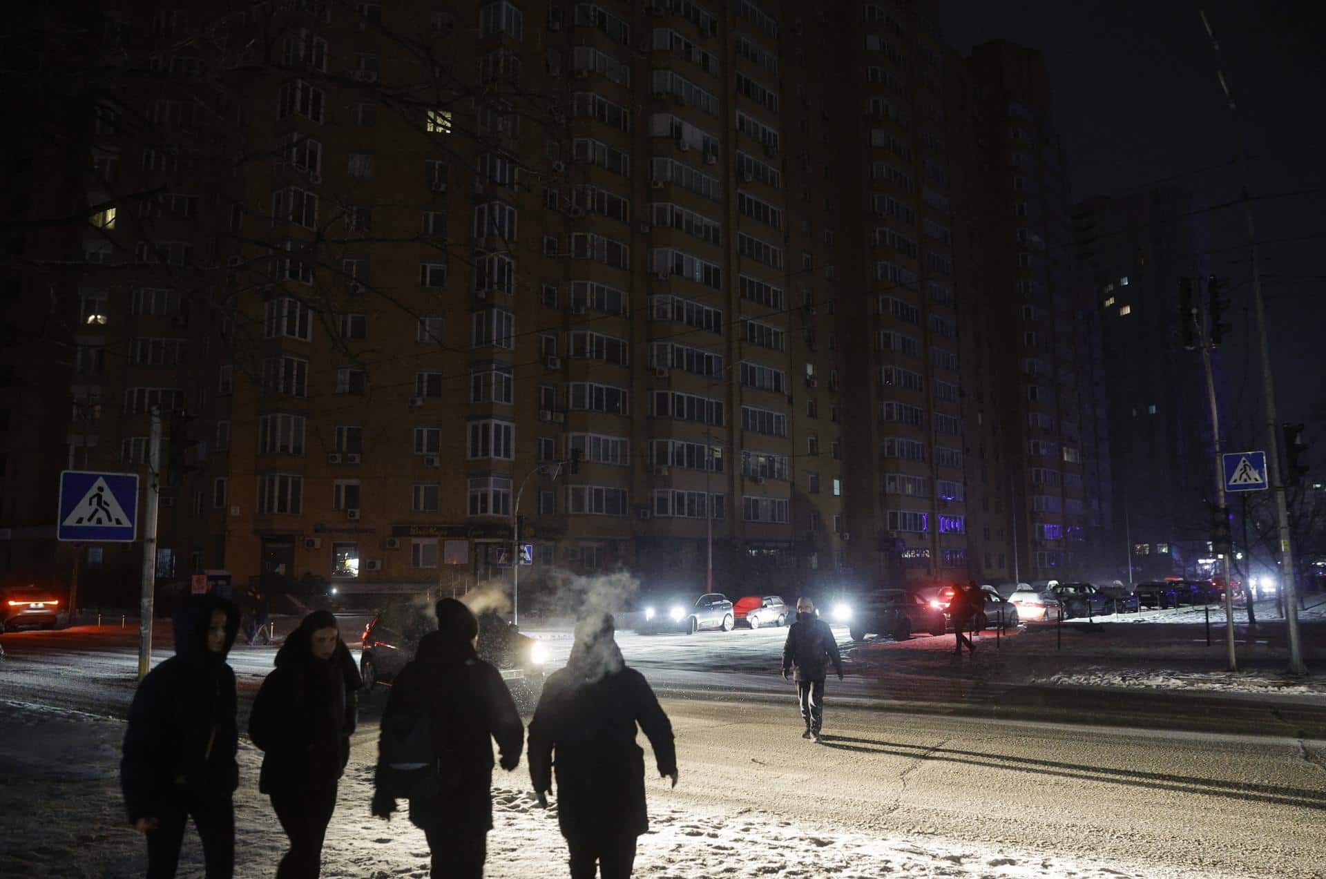 Varias personas caminan con linternas por la calle oscura durante un corte de electricidad en Kiev, Ucrania, en una imagen del 13 de enero de 2026. EFE/EPA/SERGEY DOLZHENKO