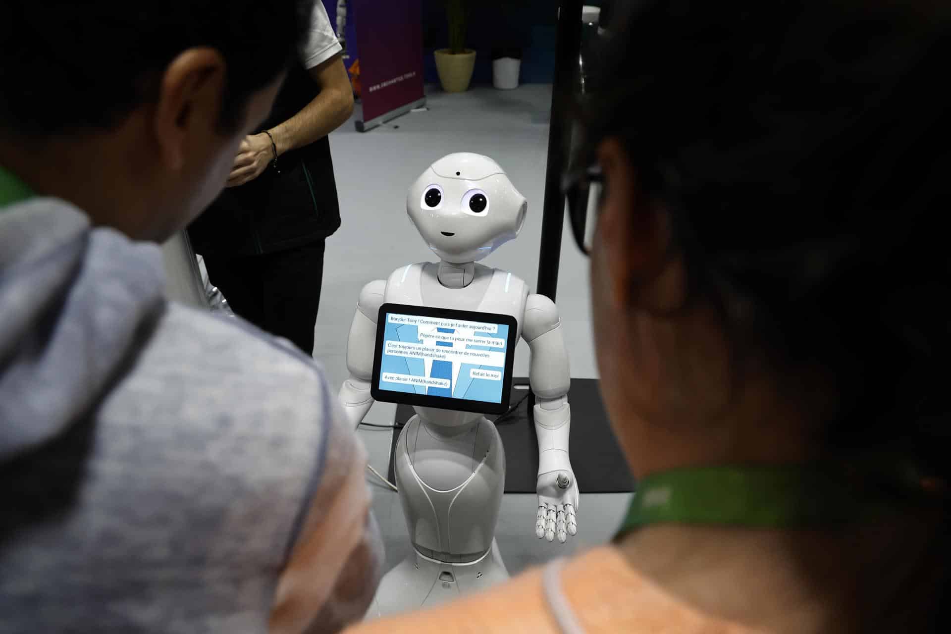 Unos visitantes hablan con el robot 'Pepper' en una imagen de archivo de una feria. EFE/EPA/SEBASTIEN NOGIER