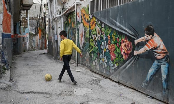 Un niño juega con una pelota en Silwán, un barrio árabe de Este de Jerusalén, donde cientos de familias están bajo amenaza de demolición de sus viviendas por parte del Gobierno israelí. EFE/Magda Gibelli
