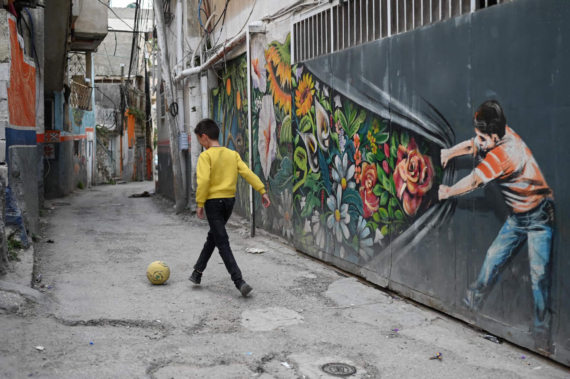 Un niño juega con una pelota en Silwán, un barrio árabe de Este de Jerusalén, donde cientos de familias están bajo amenaza de demolición de sus viviendas por parte del Gobierno israelí. EFE/Magda Gibelli