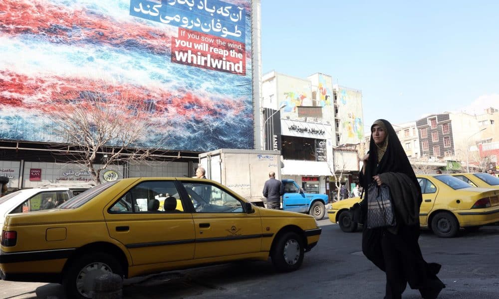 Una mujer iraní pasa frente a un cartel antiestadounidense en Teherán, Irán, el 25 de febrero de 2026. Irán y Estados Unidos mantienen este jueves una tercera ronda de negociaciones en Ginebra en busca de un acuerdo nuclear en medio de las amenazas de una intervención armada del presidente estadounidense, Donald Trump, quien ha realizado el mayor despliegue militar en Oriente Medio desde la guerra de Irak.  EFE/EPA/ABEDIN TAHERKENAREH