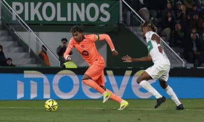 El delantero del FC Barcelona, Lamine Yamal (i), se lleva el balón ante el defensa del Elche, John Donald, durante el encuentro correspondiente a la jornada 22 de la Liga EA Sports que han disputado Elche y FC Barcelona en el estadio Martínez Valero, en la localidad alicantina. EFE / Pablo Miranzo.