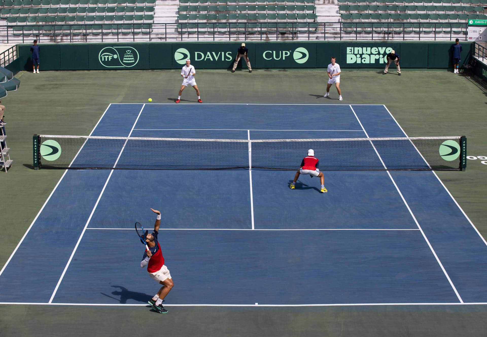 En la parte inferior, los dominicanos Peter Bertrán (c-d) y Nick Hardt (i) abren una nueva ofensiva en el partido de dobles de la serie de Copa Davis que ganaron este sábado a los letones Robert Strombachs y Karlis Ozolins. EFE/Orlando Barría