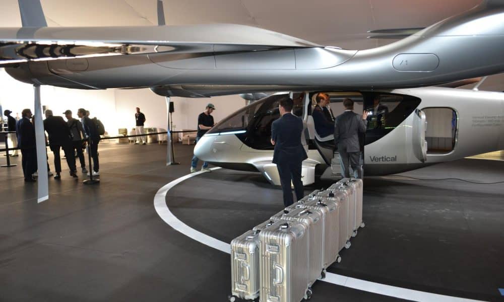 Unas personas preparan las maletas frente a un taxi volador eléctrico de la compañía Vertical Aerospace expuesto el martes 24 de febrero en Miami Beach, Florida. EFE/Antoni Belchi