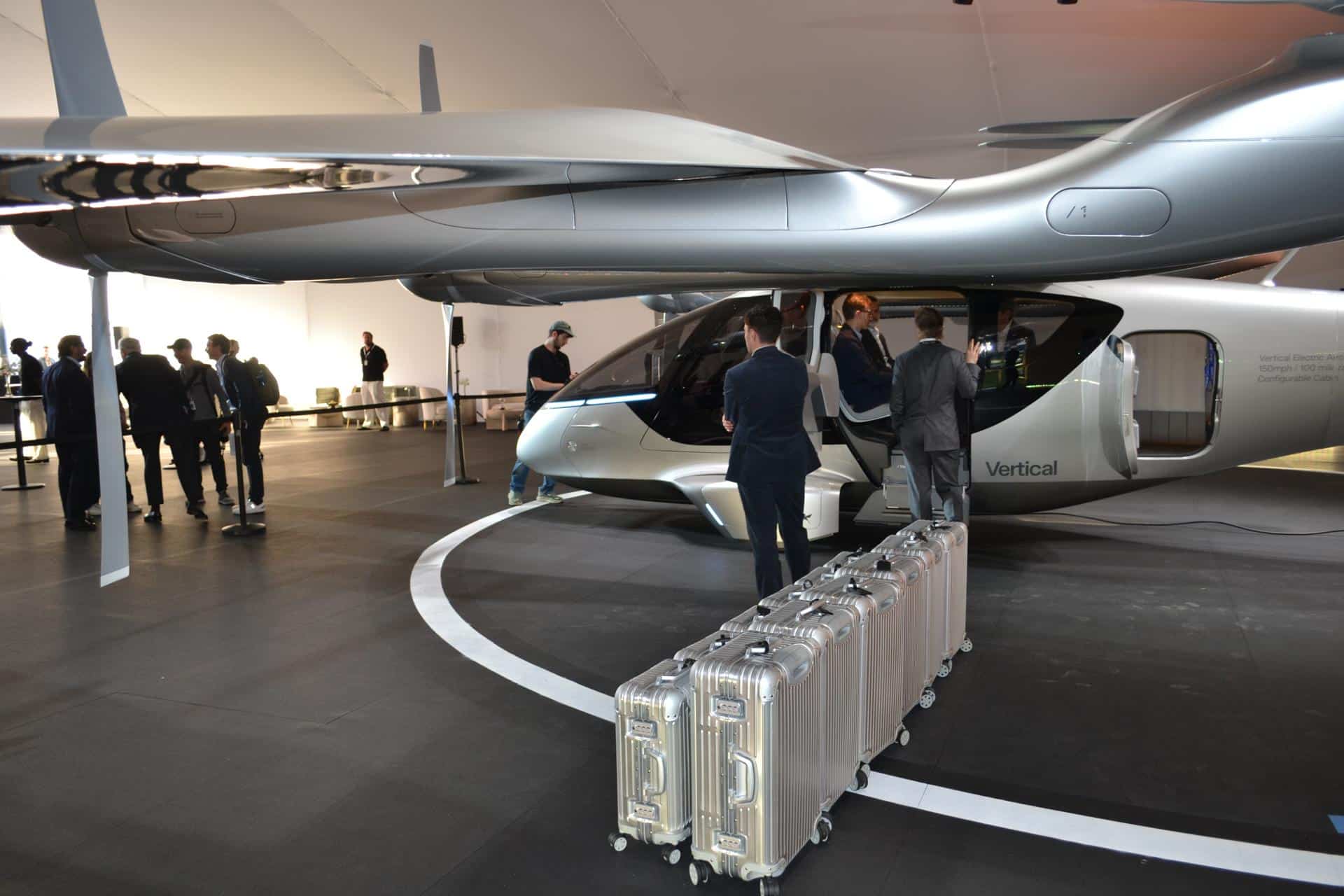 Unas personas preparan las maletas frente a un taxi volador eléctrico de la compañía Vertical Aerospace expuesto el martes 24 de febrero en Miami Beach, Florida. EFE/Antoni Belchi