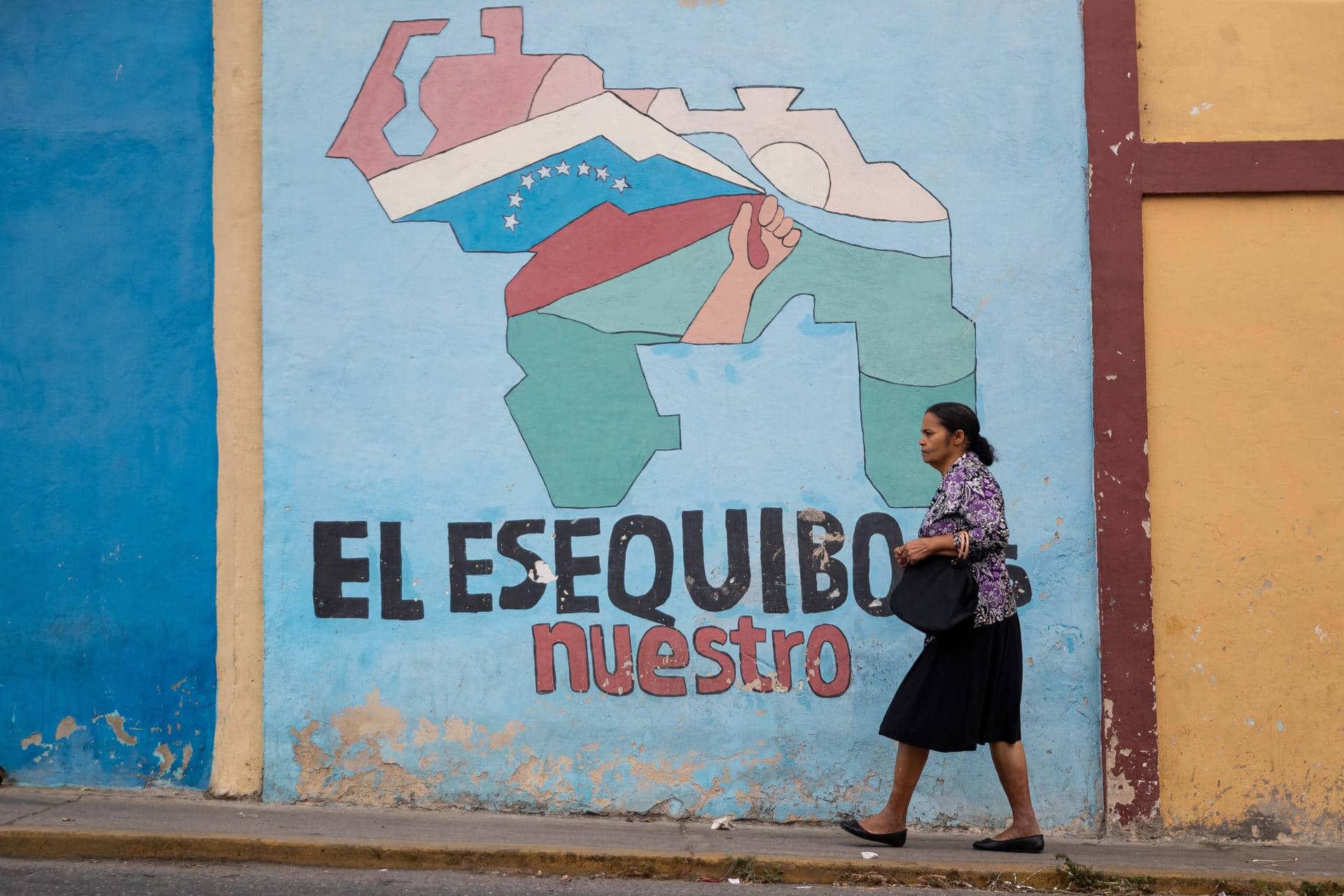 Fotografía de archivo que muestra a una persona caminando frente a un muro con un mensaje alegórico al territorio del Esequibo, en Caracas (Venezuela). EFE/ Ronald Peña
