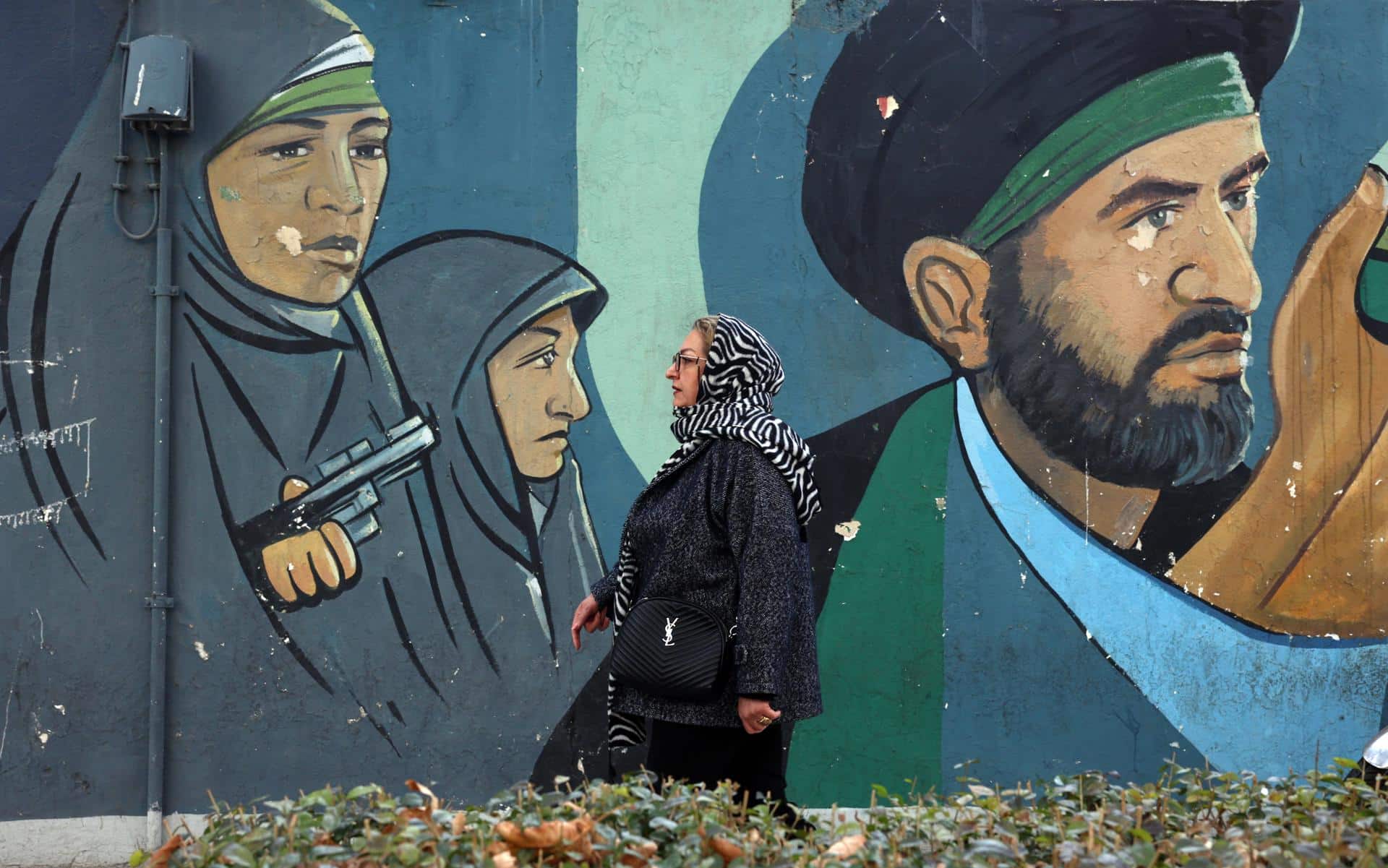 Una mujer iraní camina junto a un mural de soldados iraníes en Teherán, Irán, en una imagen del 29 de enero de 2026. EFE/EPA/ABEDIN TAHERKENAREH