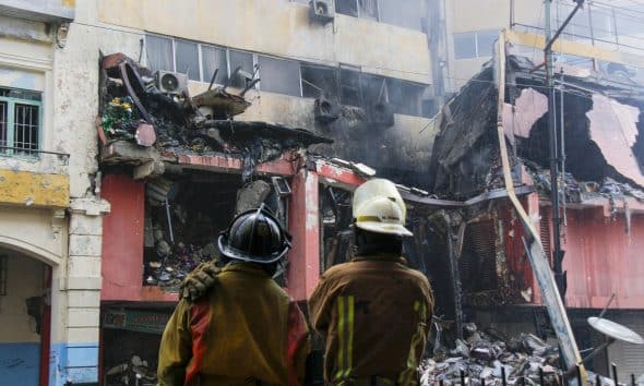 Integrantes del Cuerpo de Bomberos observan un edificio afectado por un incendio en Quito (Ecuador). EFE/ Gerardo Menoscal