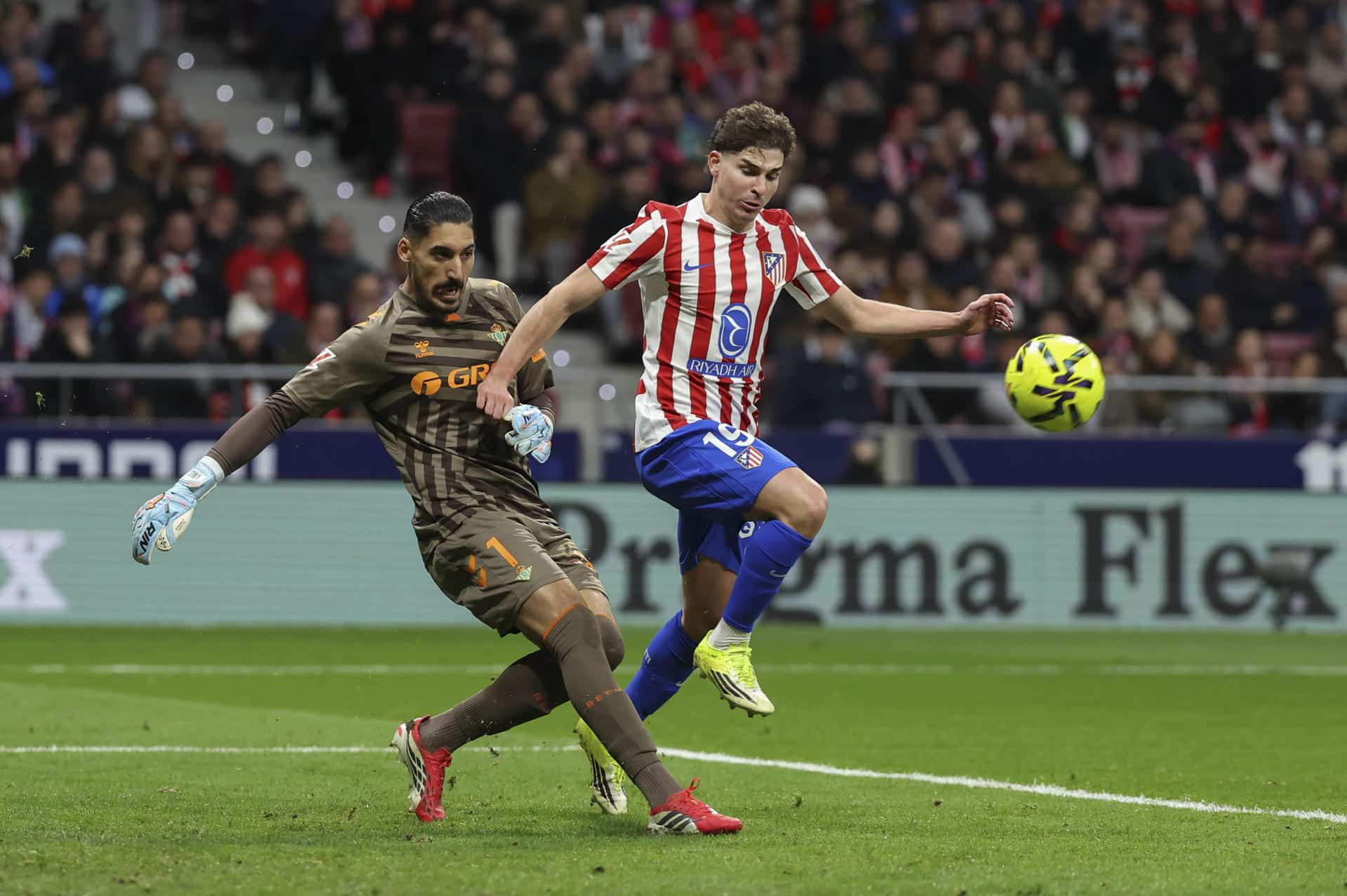 El delantero del Atlético Julián Álvarez (d) pelea un balón con el portero Álvaro Vallés, del Betis, durante el partido de LaLiga de fútbol que Atlético de Madrid y Real Betis disputaron en el Metropolitano. EFE/Kiko Huesca