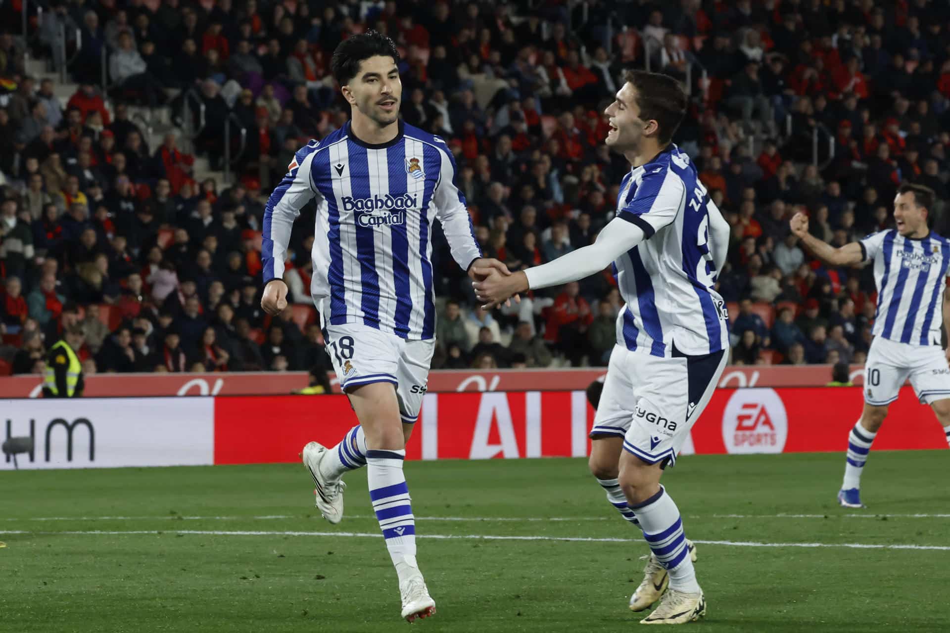 El delantero de la Real Sociedad Carlos Soler (i) celebra su gol, el primero del equipo donostiarra, durante el partido de la jornada 26 de LaLiga entre el RCD Mallorca y la Real Sociedad, este sábado en el estadio de Son Moix, en Palma.- EFE/ Cati Cladera