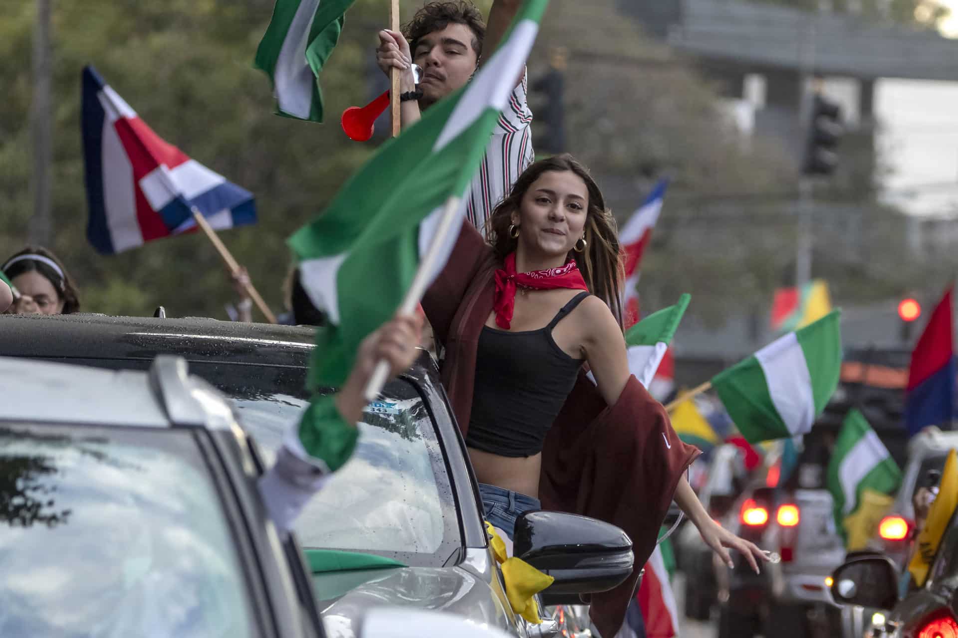 Personas sostienen banderas de diferentes partidos políticos de Costa Rica este domingo, en la fuente de la Hispanidad en San José (Costa Rica). EFE/ Alexander Otárola