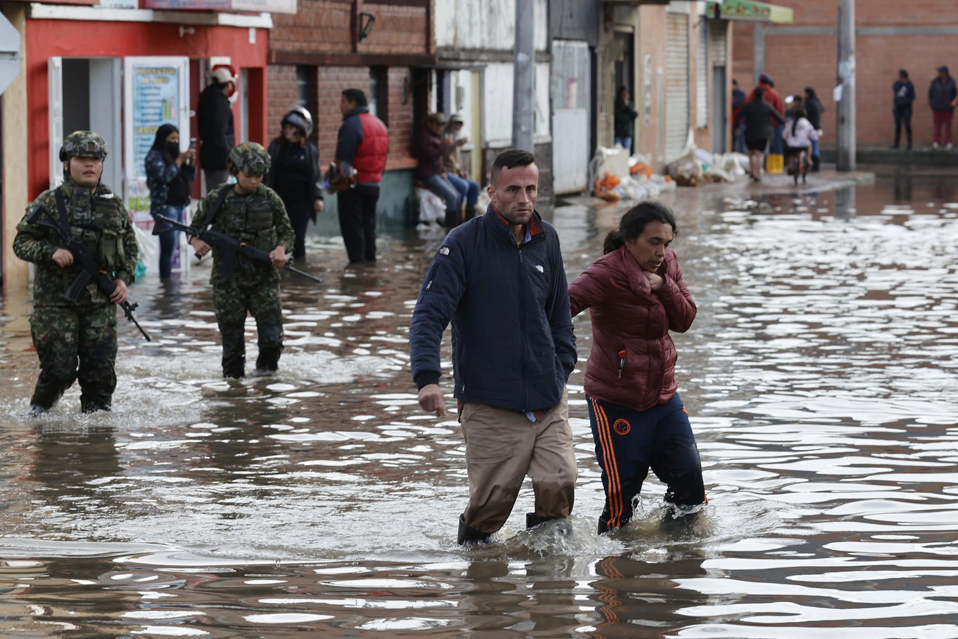 Personas caminan junto a integrantes del Ejército de Colombia en una calle inundada por las fuertes lluvias este jueves, en Facatativá (Colombia). EFE/ Mauricio Dueñas Castañeda