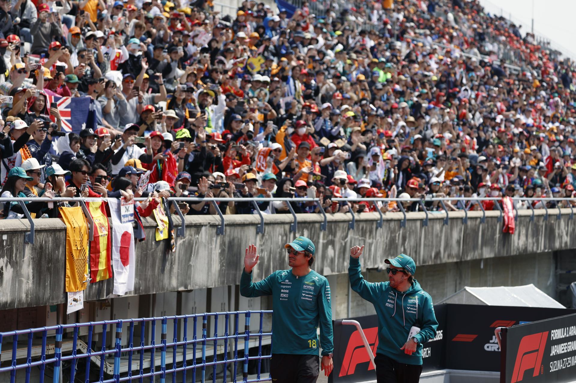 El piloto canadiense de Aston Martin Lance Stroll (izquierda), y el piloto español de Aston Martin Fernando Alonso (derecha), saludan a los aficionados durante el desfile de pilotos previo al Gran Premio de Japón de Fórmula 1 en el circuito de Suzuka International Racing Course. EFE/EPA/FRANCK ROBICHON