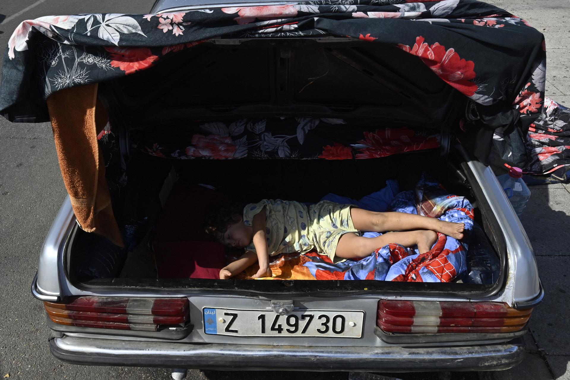 Imagen de archivo de un niño desplazado, que duerme en el maletero de un coche en una calle de Beirut. EFE/ Wael Hamzeh