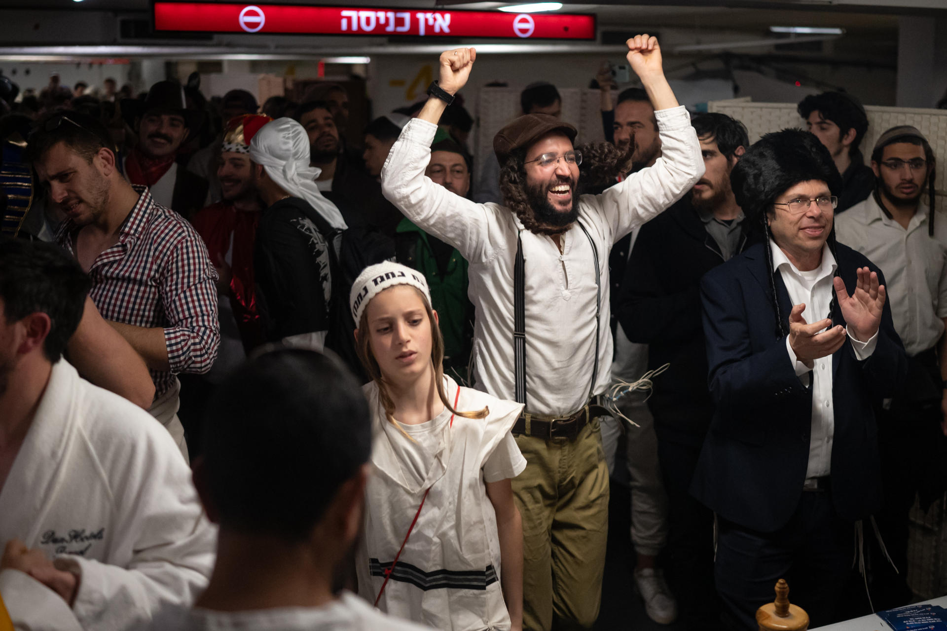 Refugiados de los misiles en el aparcamiento de un centro comercial de Tel Aviv, los israelíes celebran este lunes noche la fiesta de Purim, el carnaval judío, que conmemora precisamente la salvación del pueblo judío de los persas hace 2.500 años. EFE/ Magda Gibelli