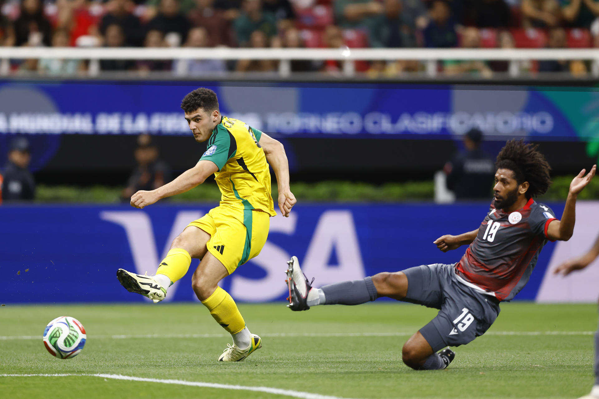 El defensor de la selección de Nueva Caledonia Joseph Athale (d) llega tarde para neutralizar el avance del goleador jamaiquino Bailey Cadamarteri (i) durante el partido de repesca jugado este jueves en el Estadio Akron de la ciudad mexicana de Guadalajara. EFE/ Francisco Guasco