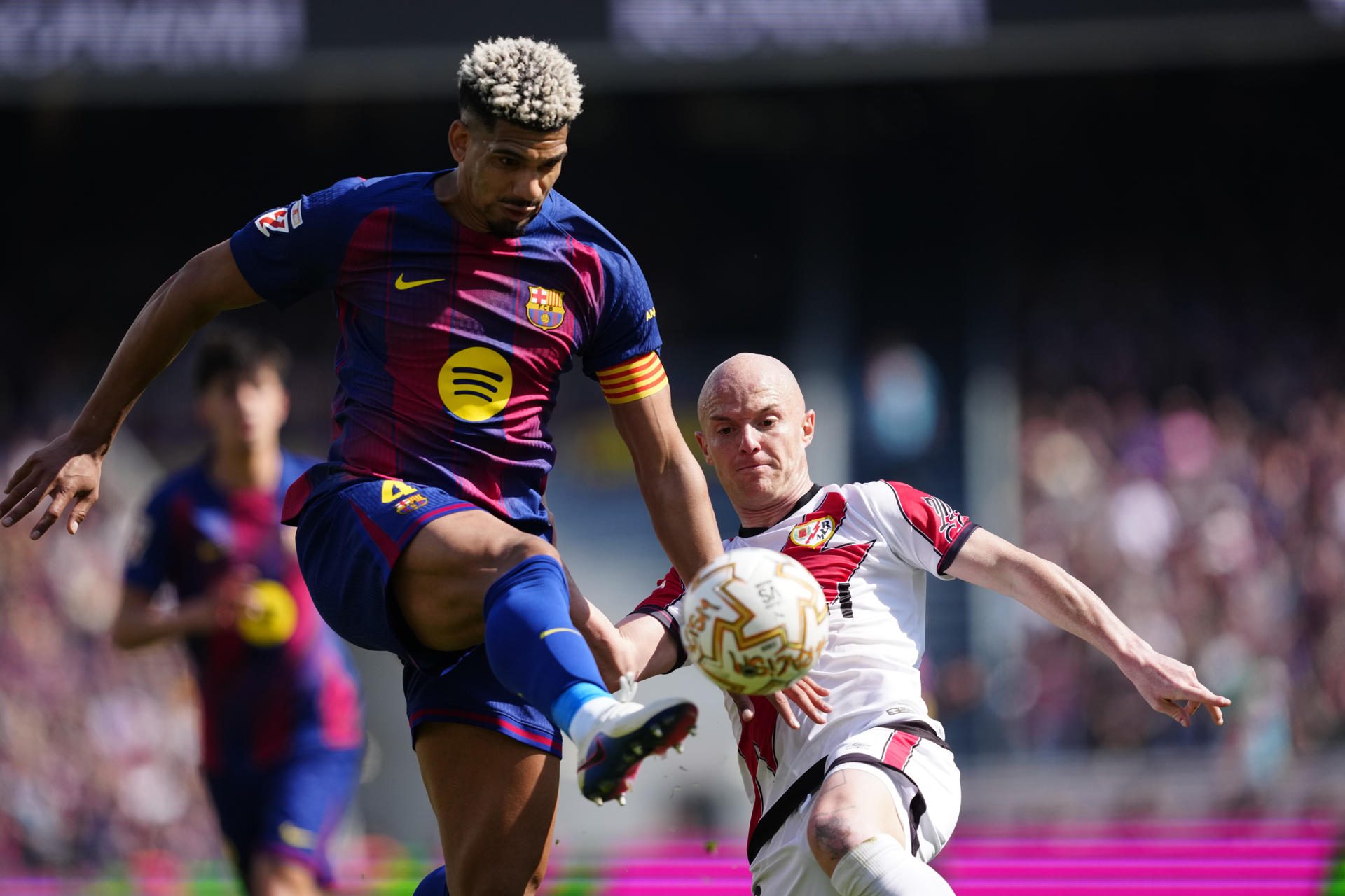 El jugador del FC Barcelona Ronald Araujo (i) lucha por el balón con Isi (d), del Rayo Vallecano, durante su partido de la jornada 29 de LaLiga EA Sports en el Camp Nou, este domingo. EFE/ Alejandro Garcia