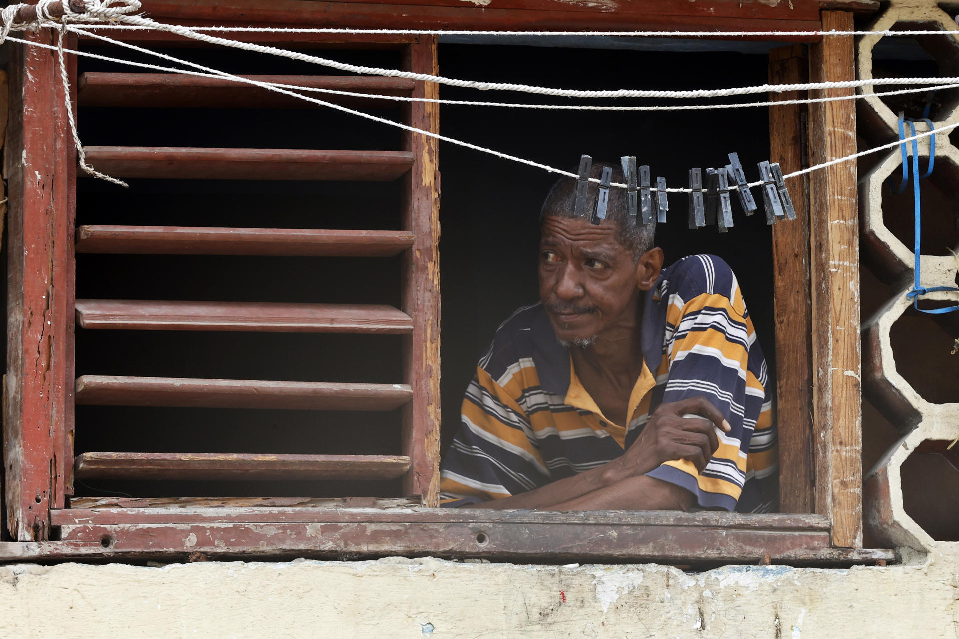 Un hombre observa desde una ventana durante un apagón en La Habana (Cuba). EFE/ Ernesto Mastrascusa
