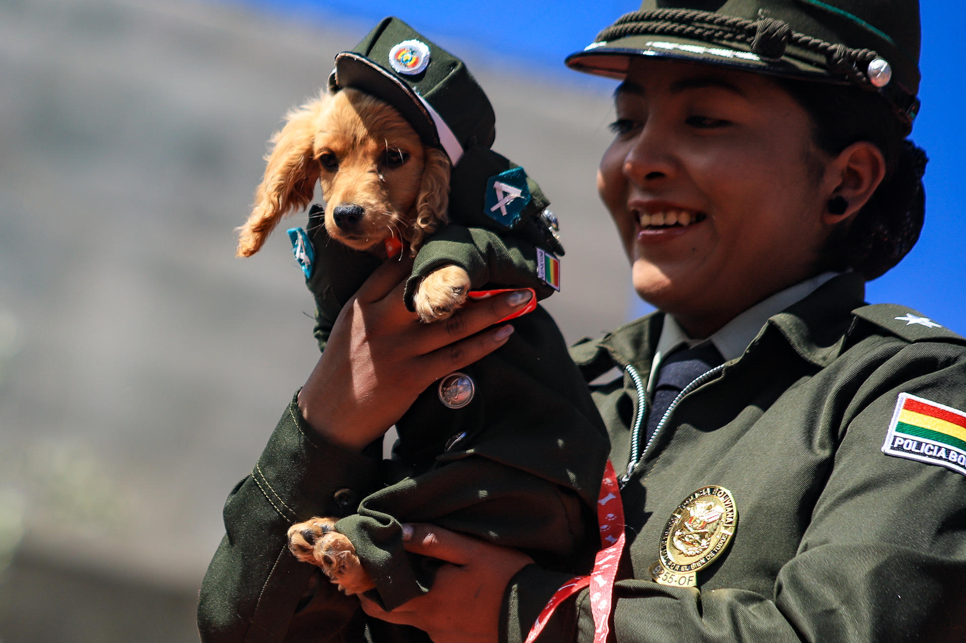Una integrante de la Policía sostiene un perro disfrazado durante un desfile este sábado, en La Paz (Bolivia). EFE/Gabriel Márquez
