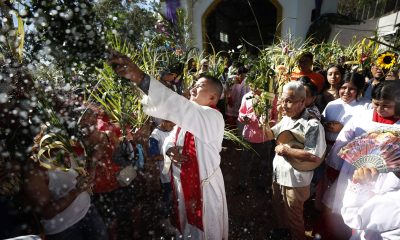 Un sacerdote esparce agua bendita durante la procesión del Domingo de Ramos en Nahuizalco (El Salvador). EFE/Rodrigo Sura