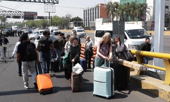 Pasajeros caminan ante un bloque de taxistas este miércoles, para llegar a la Terminal 1 del Aeropuerto Internacional de la Ciudad de México (México). EFE/Madla Hartz
