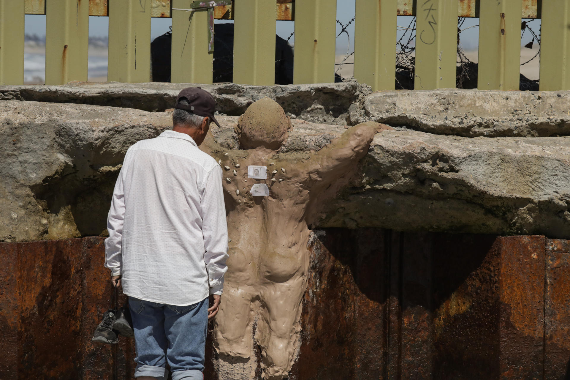 Una persona observa una escultura de barro este sábado, en el muro fronterizo en Tijuana (México). EFE/ Joebeth Terríquez