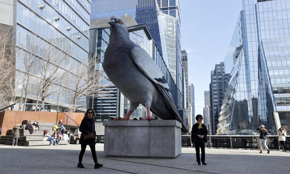 Personas caminan cerca de la escultura hiperrealista 'Dinosaur', una paloma de seis metros de altura de aluminio fundido pintada a mano por el artista colombiano Iván Argote este viernes, en el High Line de Manhattan en Nueva York (EE.UU.). EFE/ Sarah Yáñez-richards