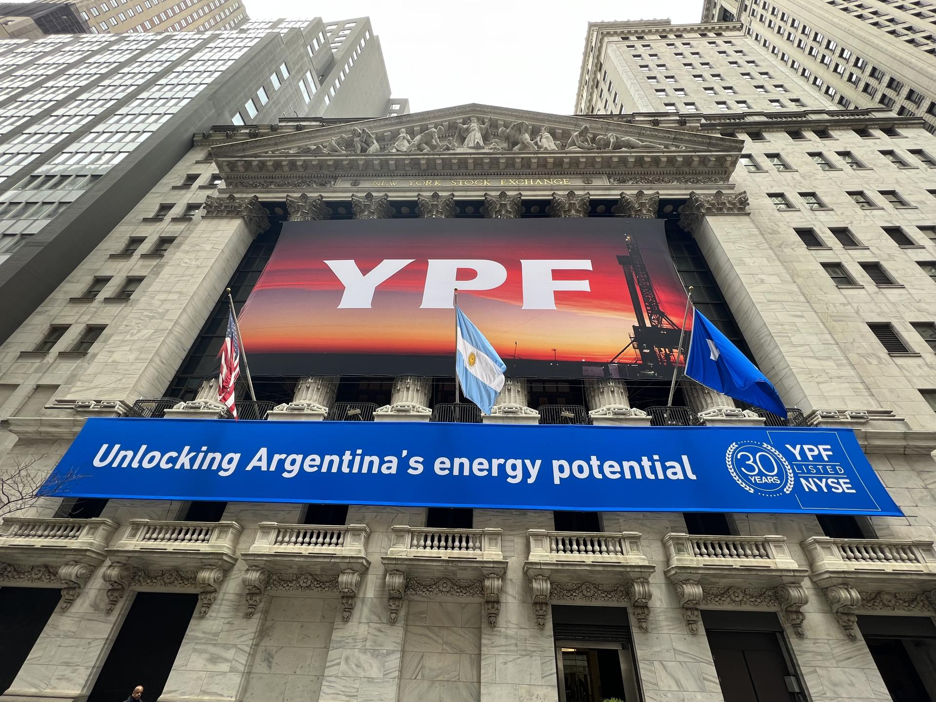 Fotografía de archivo que muestra la bandera de Estados Unidos y la bandera de Argentina mientras ondean encima de una enrome pancarta de la petrolera argentina YPF en la fachada de la bolsa de valores de Nueva York. EFE/Sarah Yáñez-Richards