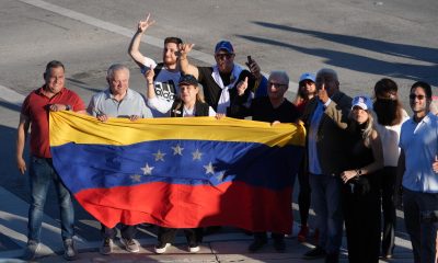 Ciudadanos venezolanos sostienen una bandera de su país esperando la llegada del presidente de Estados Unidos, Donald Trump, al restaurante venezolano El Arepazo este lunes, en Doral, aproximadamente a 14-15 millas de Miami (Estados Unidos). EFE/Alberto Boal