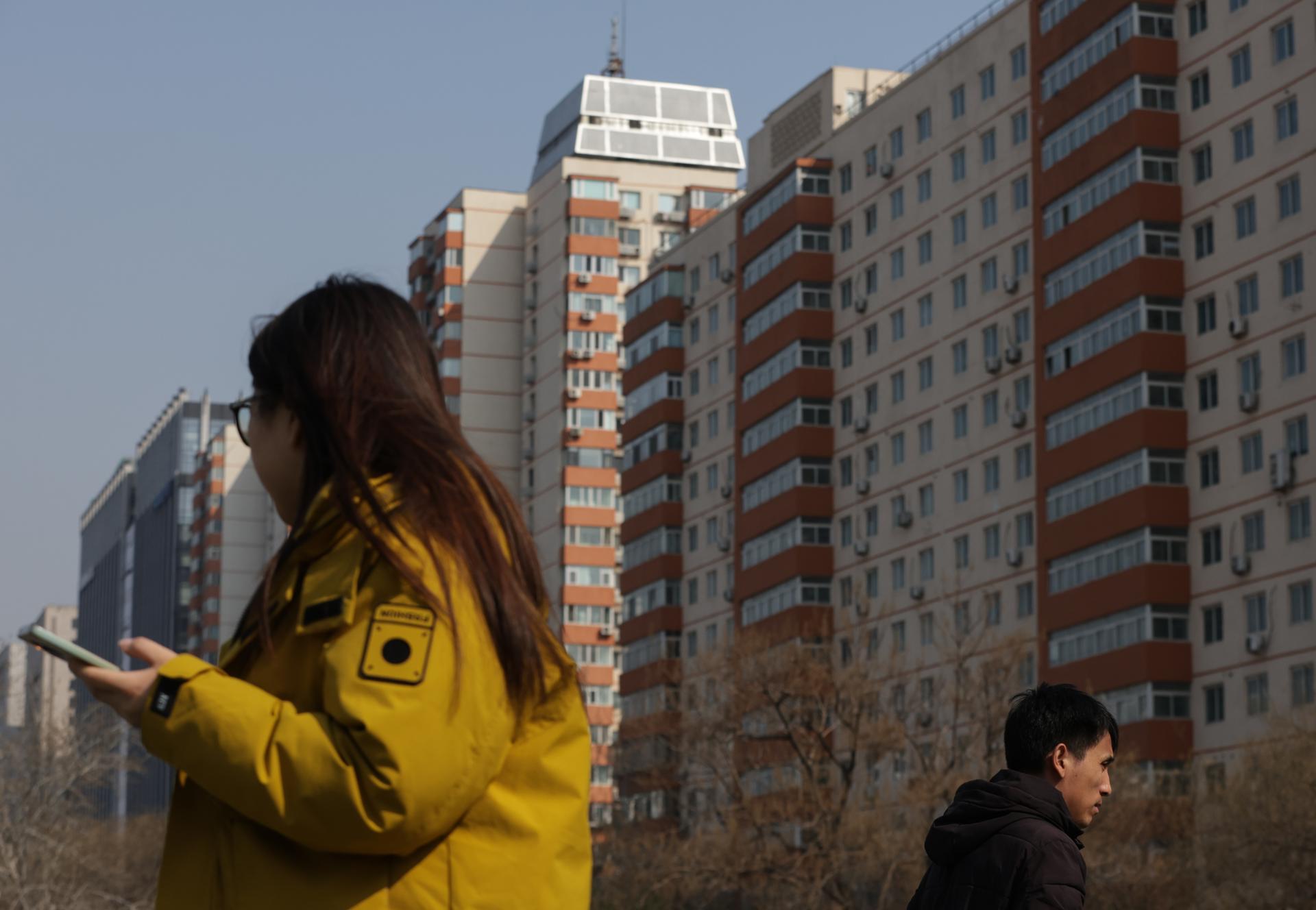 PEKÍN (China), 16/03/2026.- Varias personas caminan junto a edificios de viviendas en Pekín, China. EFE/EPA/JESSICA LEE