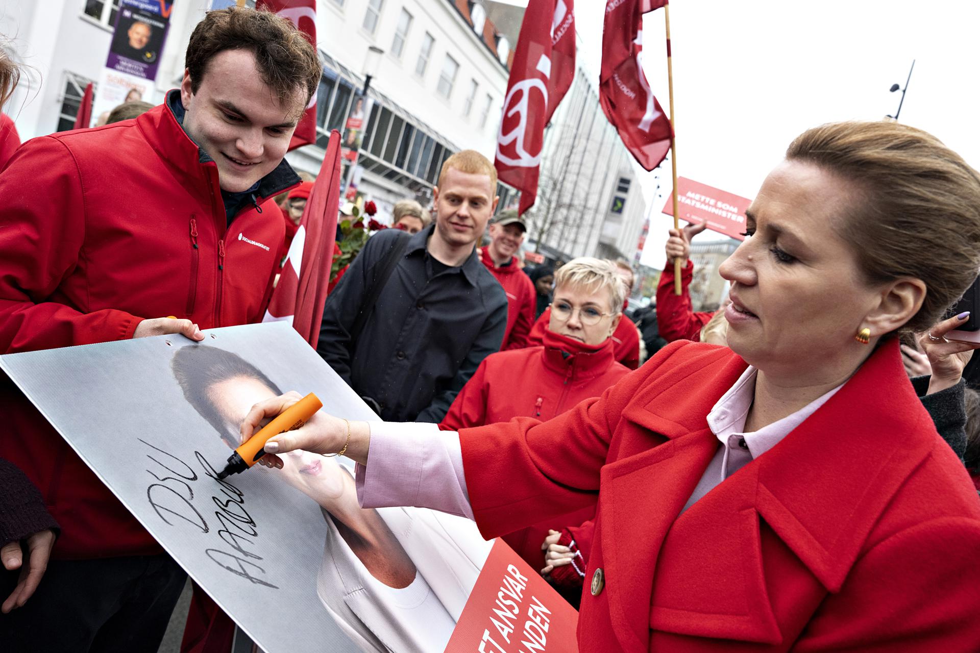 La primera ministra de Dinamarca y líder de los socialdemócratas, Mette Frederiksen (d), firma un cartel electoral mientras se reúne con votantes el día de las elecciones, en la plaza Nytorv, en Aalborg, Dinamarca, el 24 de marzo de 2026. EFE/EPA/HENNING BAGGER DENMARK OUT