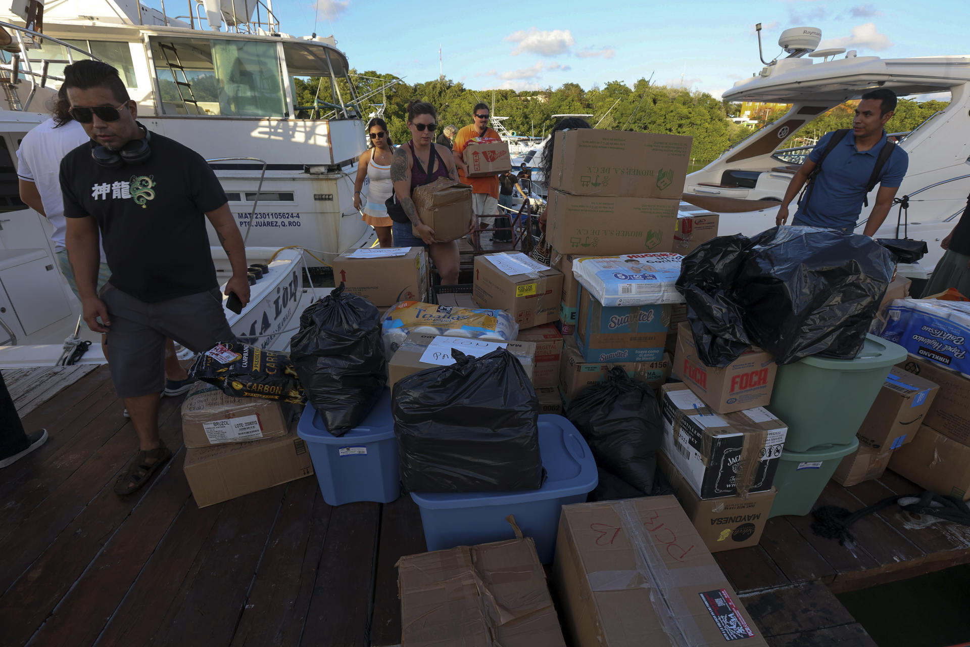 Personas cargan paquetes con ayuda humanitaria para un barco que zarpará hacia Cuba desde Isla Mujeres, en Quintana Roo (México). EFE/ Alonso Cupul