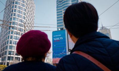 Dos personas mirando en un cartel los datos del mercado de valores de Shangai. 
EFE/EPA/ALEX PLAVEVSKI