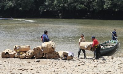 Personas descargan mercancía proveniente de Ecuador este viernes, en el cruce irregular sobre el río San Miguel que conecta a San Miguel (Colombia) con la zona rural de Lago Agrio (Ecuador). EFE/ Carlos Ortega