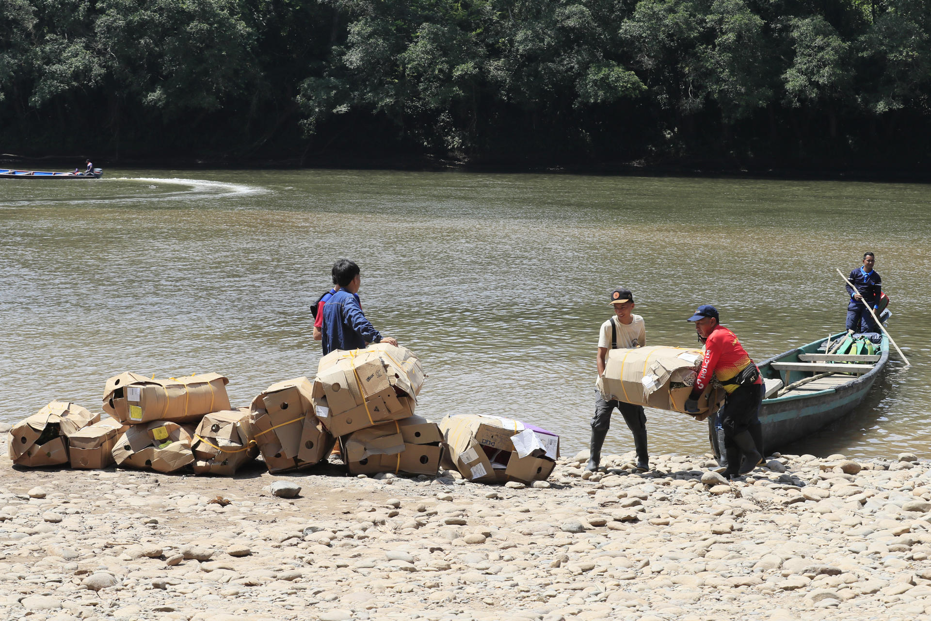 Personas descargan mercancía proveniente de Ecuador este viernes, en el cruce irregular sobre el río San Miguel que conecta a San Miguel (Colombia) con la zona rural de Lago Agrio (Ecuador). EFE/ Carlos Ortega
