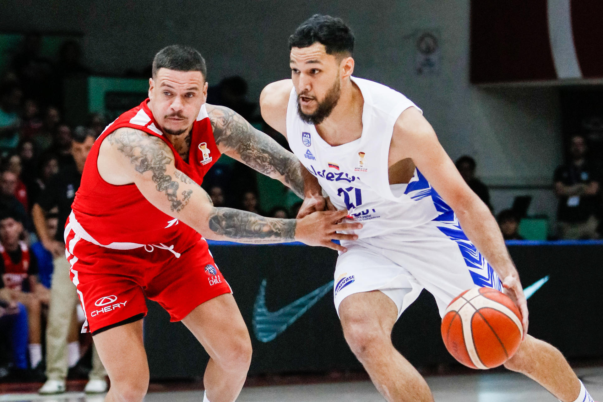El venezolano Fernando Fuenmayor (d) avanza ante la marca del chileno Sebastián Suárez (i) durante el juego clasificatorio para el Mundial de baloncesto de Catar en el coliseo Antonio Azurmendy Riveros de la ciudad de Valdivia. EFE/ Carlos Barahona