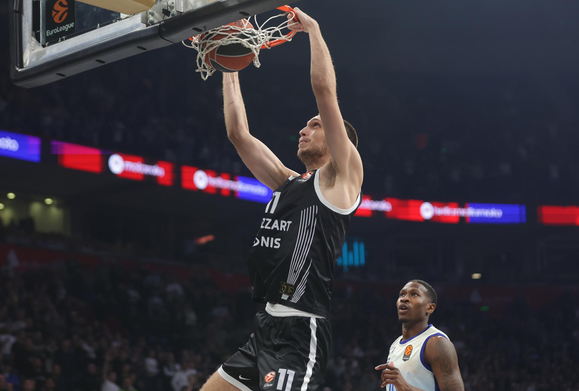 El jugador del Partizan Aleksej Pokusevski machaca el aro ante la mirada del jugador del Valencia Omari Moore (d) durante el partido de la Euroliga en Belgrado. EFE/EPA/ANDREJ CUKIC