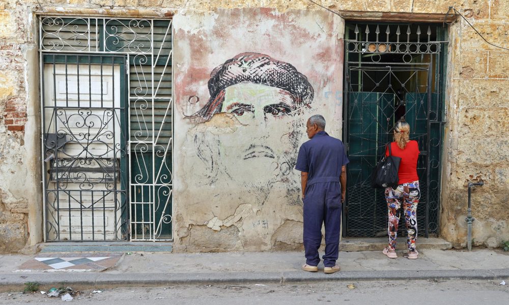 Personas esperan frente a un mural con la imagen de Ernesto 'Che' Guevara este miércoles, en La Habana (Cuba). EFE/Ernesto Mastrascusa