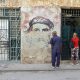 Personas esperan frente a un mural con la imagen de Ernesto 'Che' Guevara este miércoles, en La Habana (Cuba). EFE/Ernesto Mastrascusa