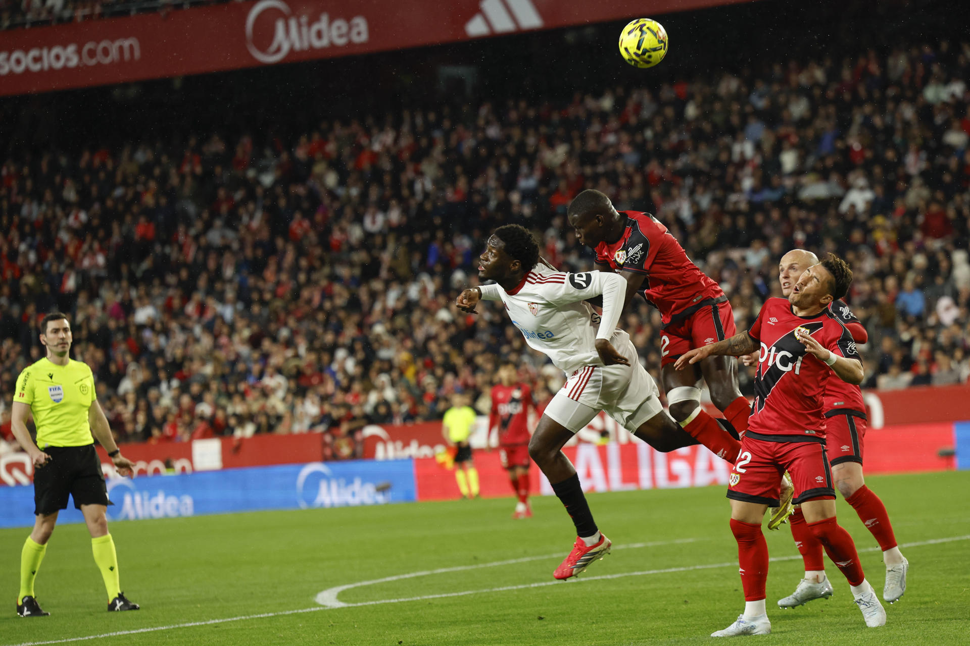 El defensa senegalés del Rayo Nobel Mendy (2i) pelea un balón aéreo con el delantero nigeriano Akor Adams (i), del Sevilla, durante el partido de la jornada 27 de LaLiga que Sevilla FC y Rayo Vallecano disputaron en el estadio Ramón Sánchez-Pizjuán. EFE/Julio Muñoz